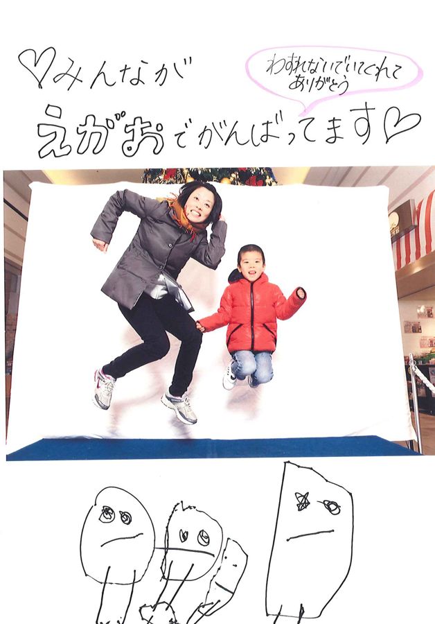 大人と子どもがジャンプした写真に「みんながえがおでがんばってます」と書き添えられている