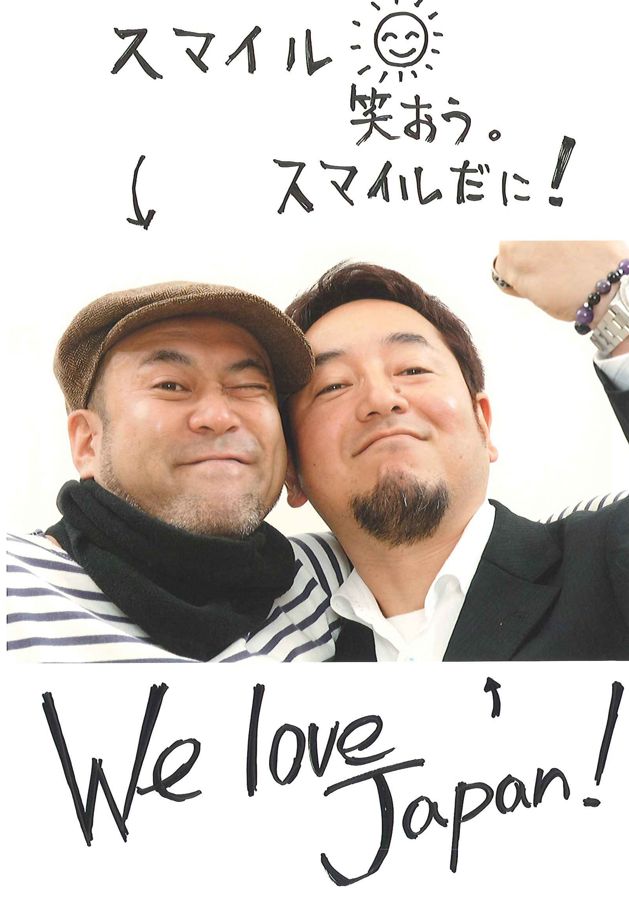 男性二人の写真に「スマイル 笑おう。」「We love Japan!」と書き添えられている